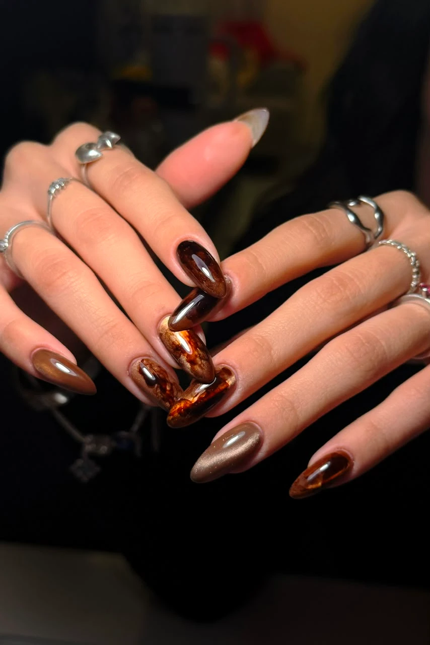 Manicura en tonos chocolate con acabados metálicos.