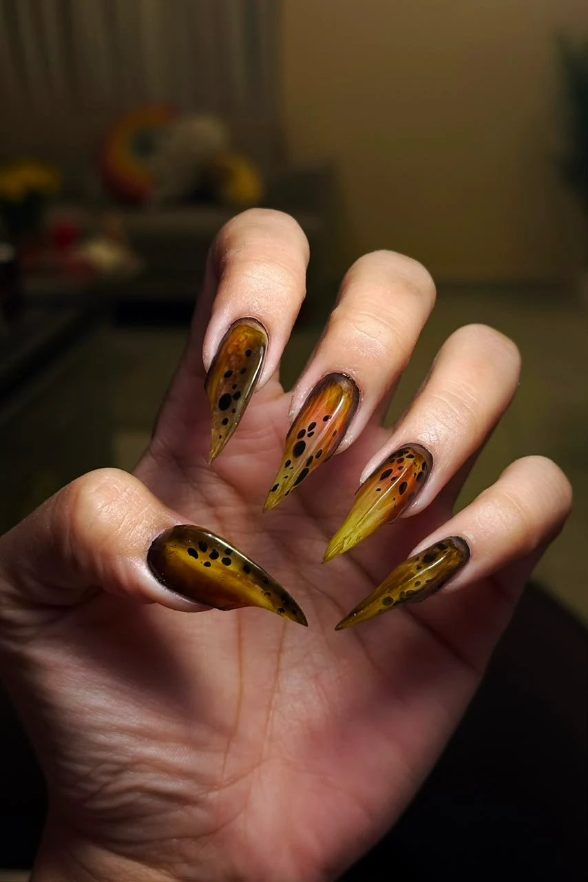 Manicura larga en amarillo, negro y efecto traslúcido.